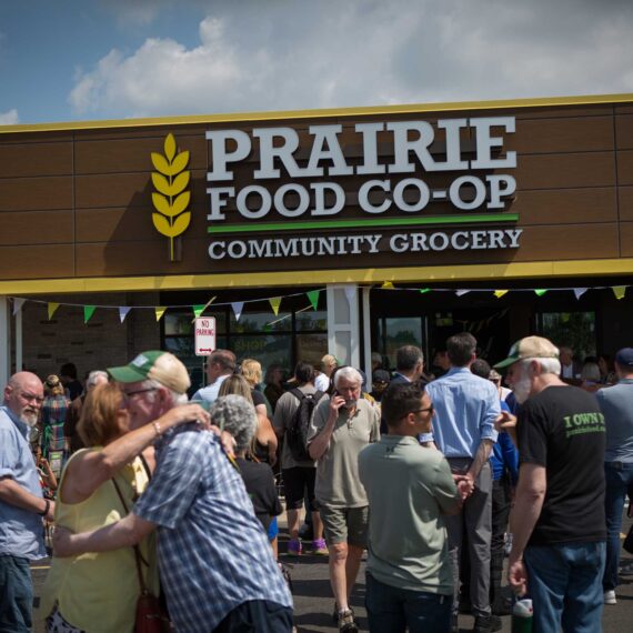 Prairie Food Co-Op exterior at grand re-opening with crowd of people entering the building.