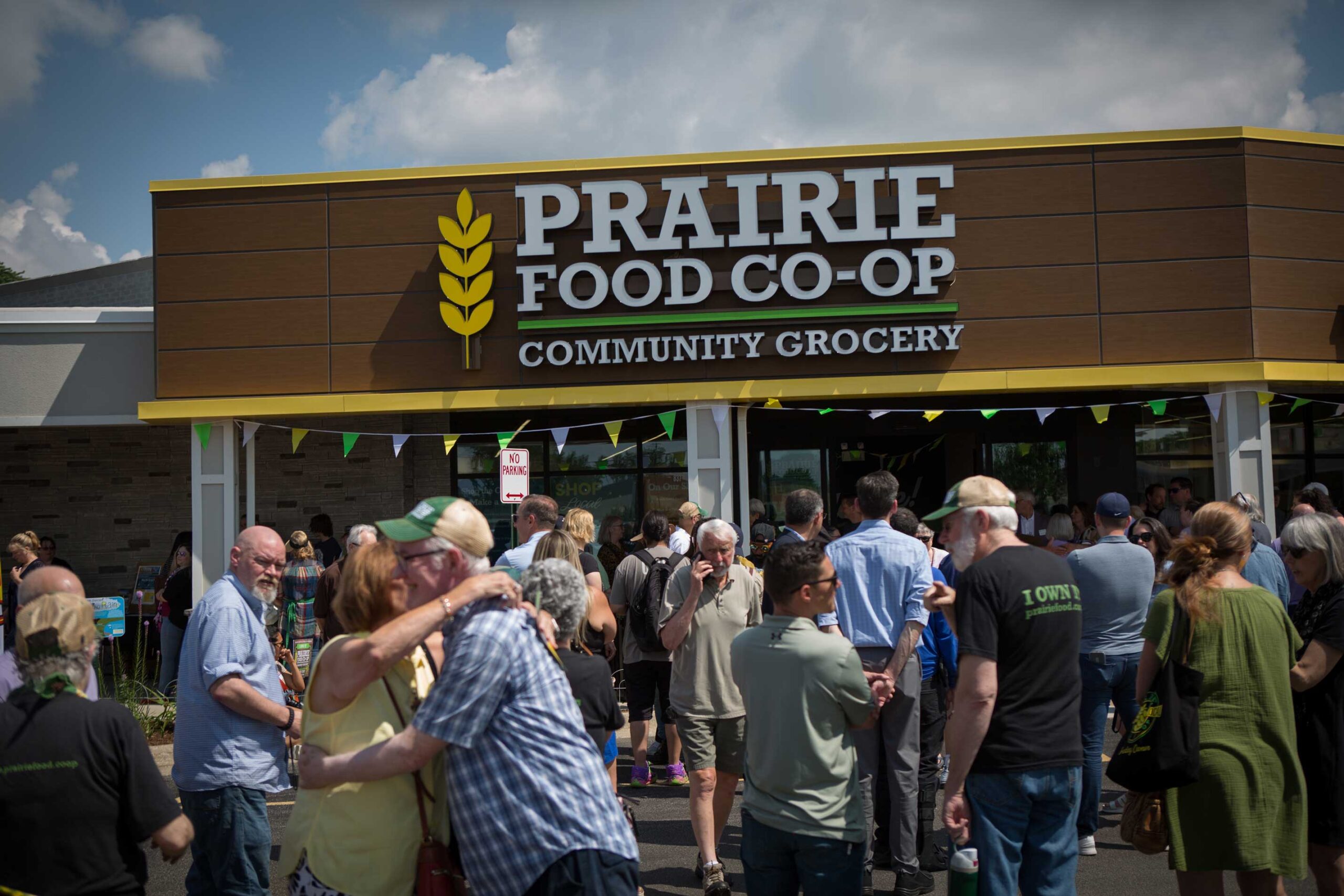 Prairie Food Co-Op exterior at grand re-opening with crowd of people entering the building.